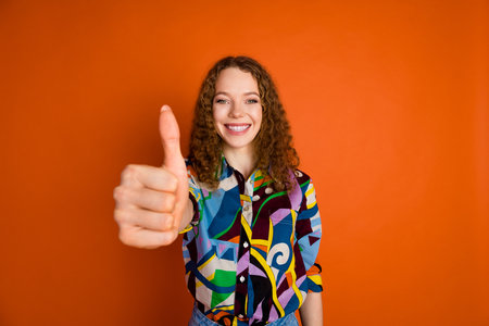 Photo of lovely nice girl wear stylish clothes thumb up isolated on vivid orange color backgroundの写真素材