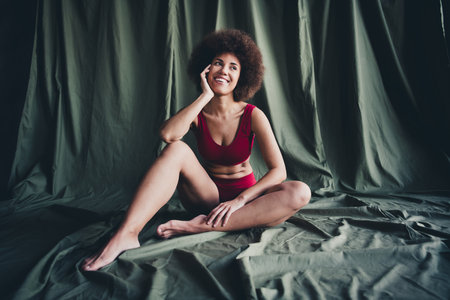 Unretouched photo of happy girl sit in lingerie look dreaming isolated green linen backgroundの写真素材