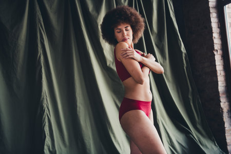 Unretouched photo of girl cuddle her hands body feel tenderness in studio interiorの写真素材