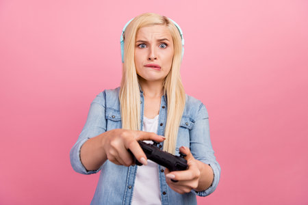 Photo of young girl bite lips anxious race speed joystick competition isolated over pink color backgroundの写真素材