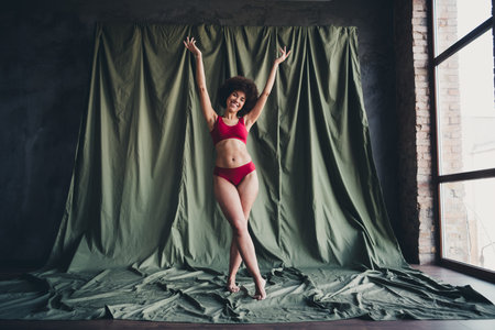 Unretouched photo of happy body positive girl raise hands up tsna dover khaki background in studio roomの写真素材