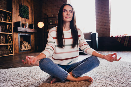 Photo of shiny adorable lady dressed striped jumper sitting floor practicing yoga indoors house room