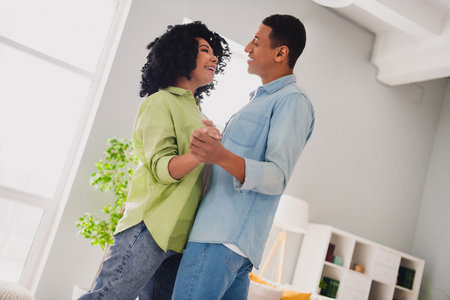 Photo of adorable charming couple dressed casual outfit dancing having fun together indoors house roomの写真素材