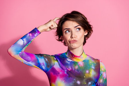 Photo of nice young woman scratch head look empty space wear pullover isolated on pink color backgroundの写真素材