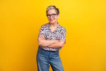 Photo portrait of pretty retired female crossed hands confident dressed stylish leopard print outfit isolated on yellow color backgroundの写真素材
