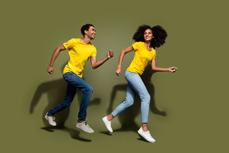 Full size profile photo of two young people rush jump wear t-shirt isolated on khaki color...