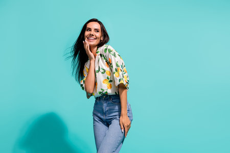 Photo of gorgeous lovely girl with long fluttering hair wear stylish shirt look at promo empty space isolated on teal color backgroundの写真素材