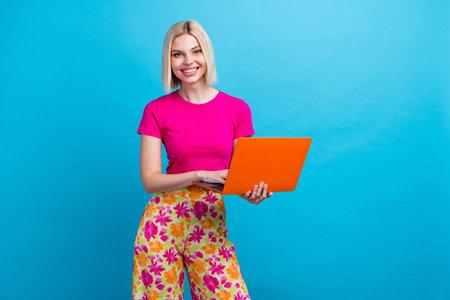 Photo portrait of lovely young lady hold netbook dressed stylish pink clothes isolated on blue color backgroundの写真素材