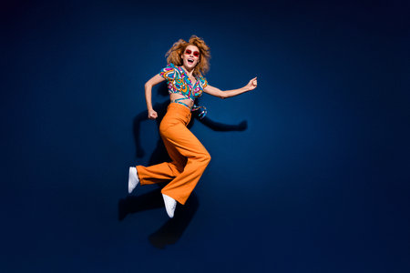 Full body profile portrait of nice young lady jump run empty space wear top isolated on dark blue...