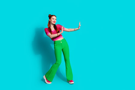 Full length photo of cheerful funky lady dressed pink knitted shirt showing arms emtpy space isolated blue color backgroundの写真素材