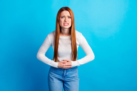 Photo portrait of attractive young woman touch stomach suffer ache dressed stylish white clothes...