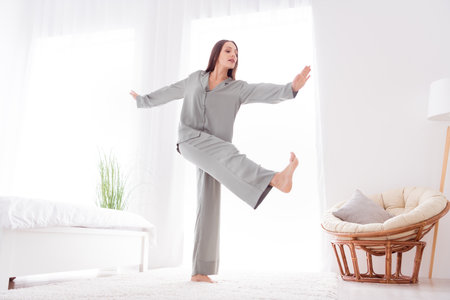 Photo of adorable sweet lady wear grey nightwear dancing having fun indoors apartment bedroomの写真素材