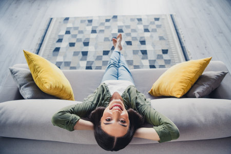 Full size high angle view photo of pretty young lady sit couch wear green shirt weekend modern apartment indoorsの写真素材