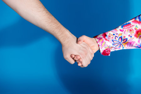 Photo of two mature young people arms hold hands couple isolated blue color backgroundの写真素材