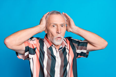Photo of worried nervous man wear striped stylish clothes hand touch head isolated on blue color backgroundの写真素材