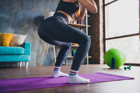 Cropped photo of sportive girl doing sit ups exercise wear new brand sportswear in home gymの写真素材