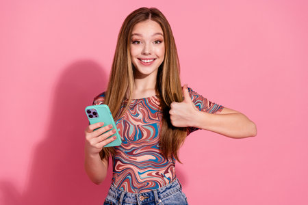 Portrait of optimistic teen with long hairstyle dressed shirt holding smartphone showing thumb up...