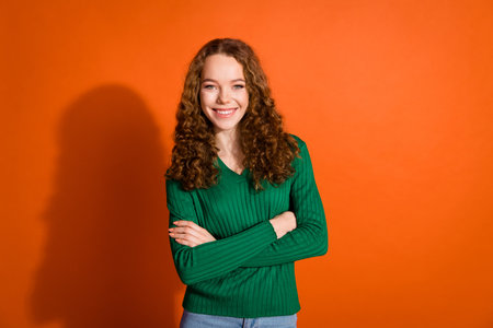 Photo of cool confident lady dressed green shirt smiling arms crossed isolated orange color backgroundの写真素材