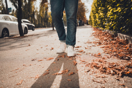 Cropped photo of man in trendy sneakers walking on road pavement sidewalk urban city street style