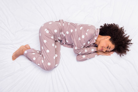 Photo of adorable pretty lady wear pajama lying bed arms hands cheek cheekbone isolated white color backgroundの写真素材