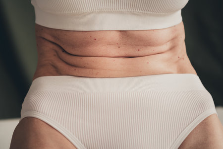 Unretouched cropped photo of old lady have aging skin on belly isolated green color backgroundの写真素材