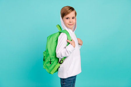 Back to school concept. Funny cool boy wear bag waiting for classroom lesson isolated cyan color backgroundの写真素材