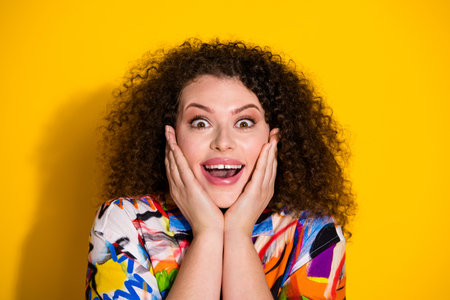 Photo portrait of pretty young girl touch cheeks amazed wear trendy colorful print outfit isolated on yellow color backgroundの写真素材