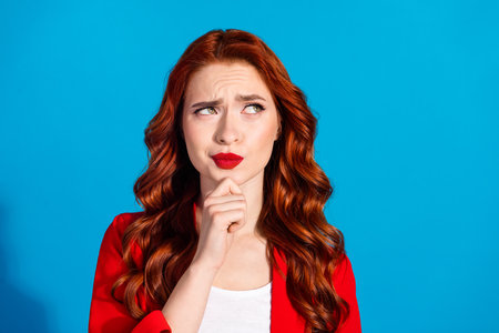 Photo of minded successful lovely girl wear red trendy clothes look empty space isolated on blue color backgroundの写真素材