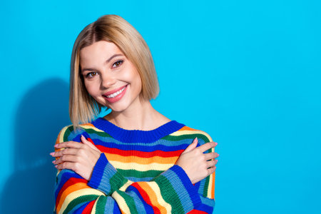 Photo portrait of pretty young girl hugging self wear trendy striped outfit isolated on blue color backgroundの写真素材