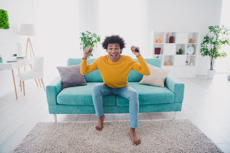 Photo of positive cheerful man sitting soft comfy divan in apartment watching movie rest relax indoorsの写真素材