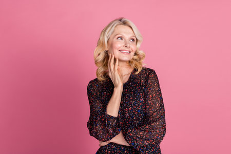 Photo of pretty aged lady look empty space think wear dress isolated on pink color backgroundの写真素材