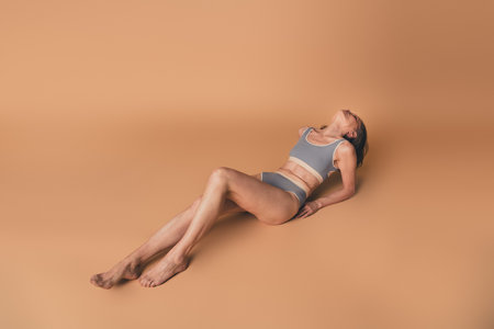 No filter photo of charming woman posing in stylish underwear isolated on beige color backgroundの写真素材