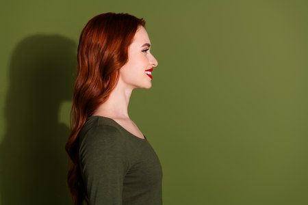 Photo of shiny attractive lady dressed shirt smiling looking empty space isolated green color backgroundの写真素材