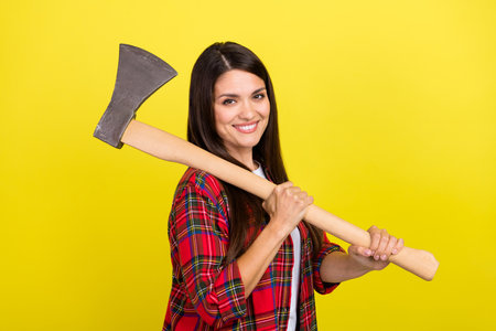 Photo of strong funny lady dressed checkered shirt holding sharp axe isolated yellow color backgroundの写真素材