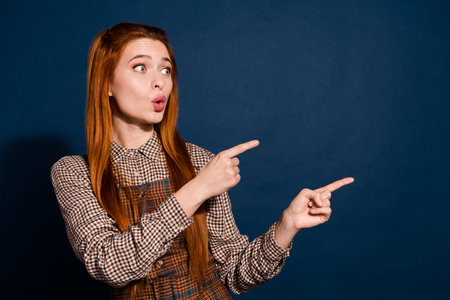 Photo of impressed cheerful lady lady dressed plaid outfit showing two fingers empty space isolated dark blue color backgroundの写真素材