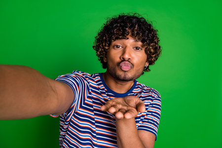 Photo of handsome nice man wear trendy clothes video live stream send kiss isolated on green color backgroundの写真素材