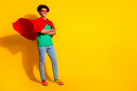 Full length photo of funny super hero costume young man folded hands empty space isolated on yellow color backgroundの写真素材