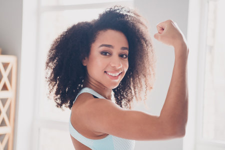 Profile photo of nice fit young woman arm showing biceps sportswear training home gym indoorsの写真素材