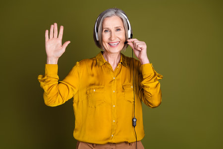 Photo of adorable positive woman wear shirt working client support service waving arm hi isolated khaki color backgroundの写真素材