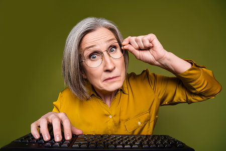Photo of doubtful shocked woman wear shirt typing keyboard empty space isolated khaki color...