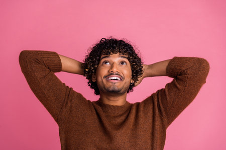 Photo of cheerful handsome man wear trendy clothes hold arms behind head empty space isolated on pink color backgroundの写真素材