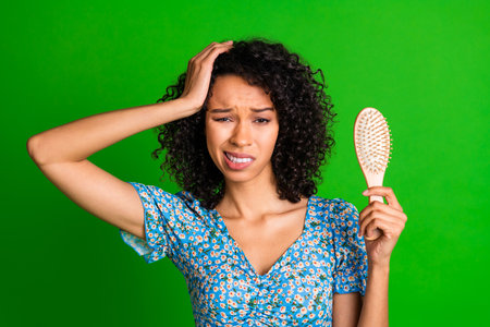 Photo of nice young woman hold brush touch head wear top isolated on green color backgroundの写真素材