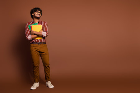 Full size photo of nice young man book look empty space wear striped shirt isolated on brown color backgroundの写真素材