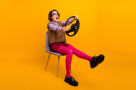 Photo portrait of attractive young woman sit chair nervous steering wheel dressed retro office clothes isolated on yellow color backgroundの写真素材