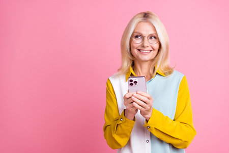 Photo of nice aged lady smart phone look empty space wear shirt isolated on pink color background