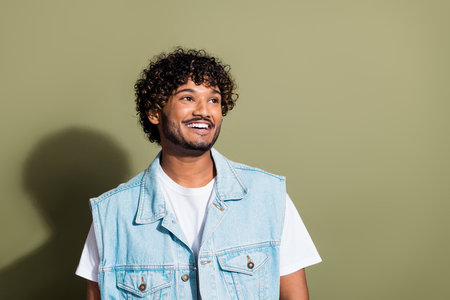 Photo portrait of handsome young guy look empty space wear trendy jeans outfit isolated on khaki color backgroundの写真素材