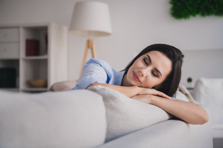 Photo of adorable good mood lady dressed blue shirt lying sofa sleeping closed eyes indoors house roomの写真素材