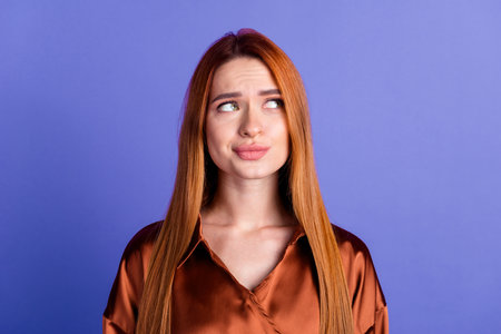 Photo of pretty young woman look empty space think wear brown shirt isolated on violet color backgroundの写真素材