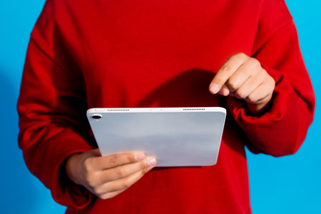 Cropped photo of lovely young lady hold tablet ebook dressed stylish red garment isolated on blue...