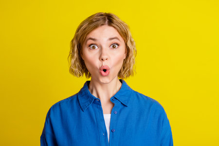 Portrait of pretty young lady pouted lips wear blue shirt isolated on yellow color backgroundの写真素材